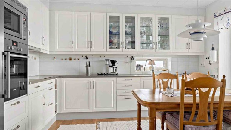 Vita köksluckor och lådfronter på ett IKEA-kök med vitrindörrar.